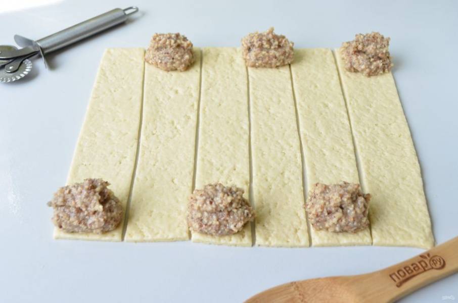 7. Раскатайте тонко тесто, порежьте на 6 полосок. На край каждой положите часть ореховой начинки.