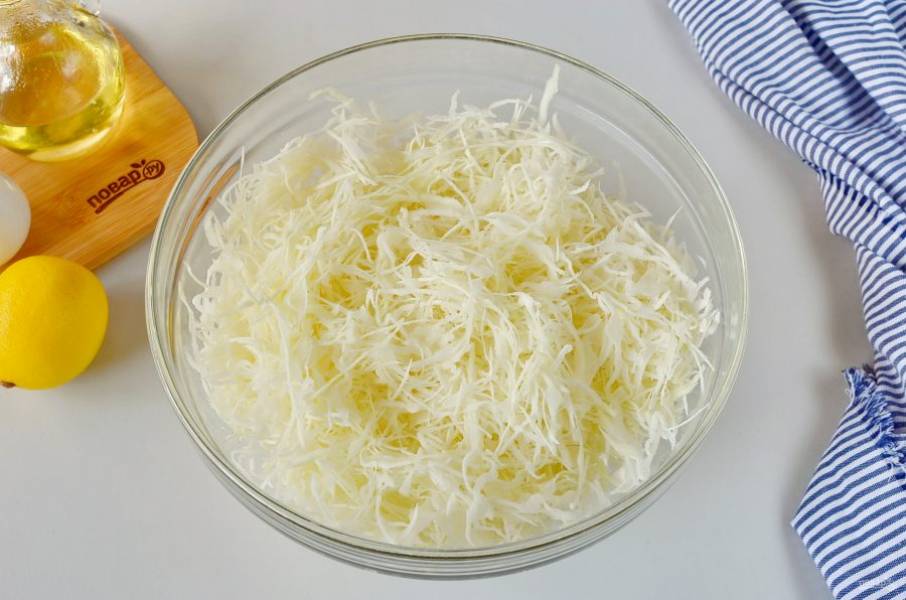 Нашинкуйте тонко капусту. Выложите в глубокий салатник.