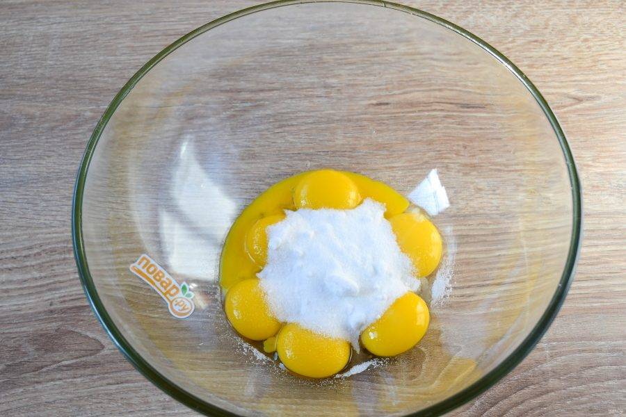 2. Яйца разделите на белки и желтки, которые поместите в разные миски. Важно: обе миски должны быть полностью чистыми и сухими. К желткам отправьте половину стакана фруктозы и взбейте миксером до посветления массы и увеличения ее в объеме.