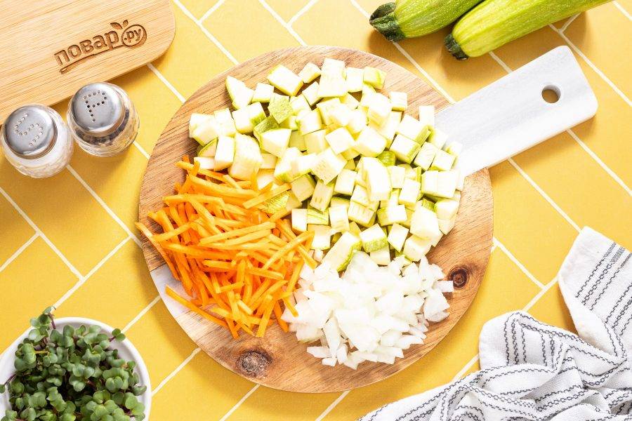 Кабачок нарежьте кубиками. Репчатый лук нарежьте на мелкие кубики, а морковь очистите и натрите на терке.