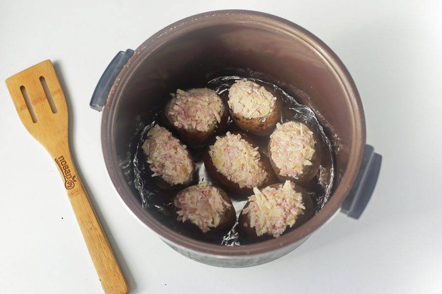 Нафаршируйте подготовленной начинкой картофель и выложите его в чашу мультиварки. Дно можно предварительно застелить фольгой. Готовьте на том же режиме около 30 минут.