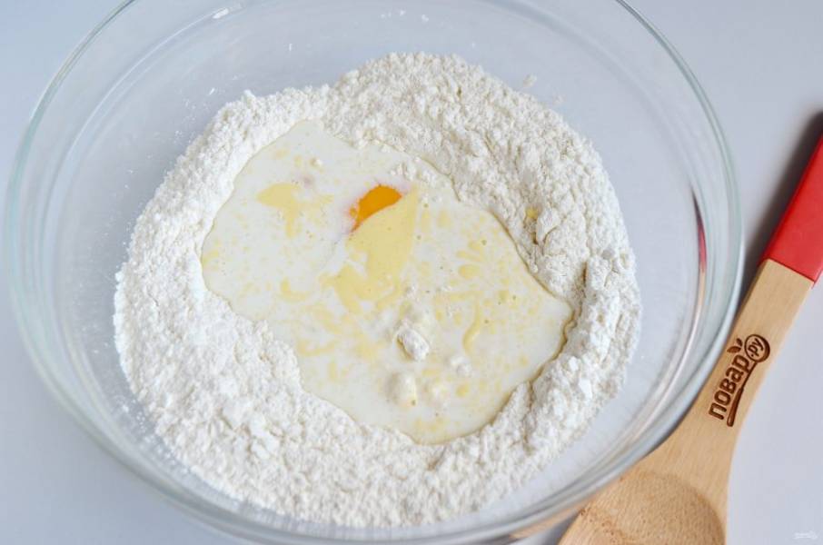 4. В муку с дрожжами влейте теплое молоко, растопленное масло и яйцо. Часть яйца, буквально десертную ложку отделите сразу для смазывания булочек.