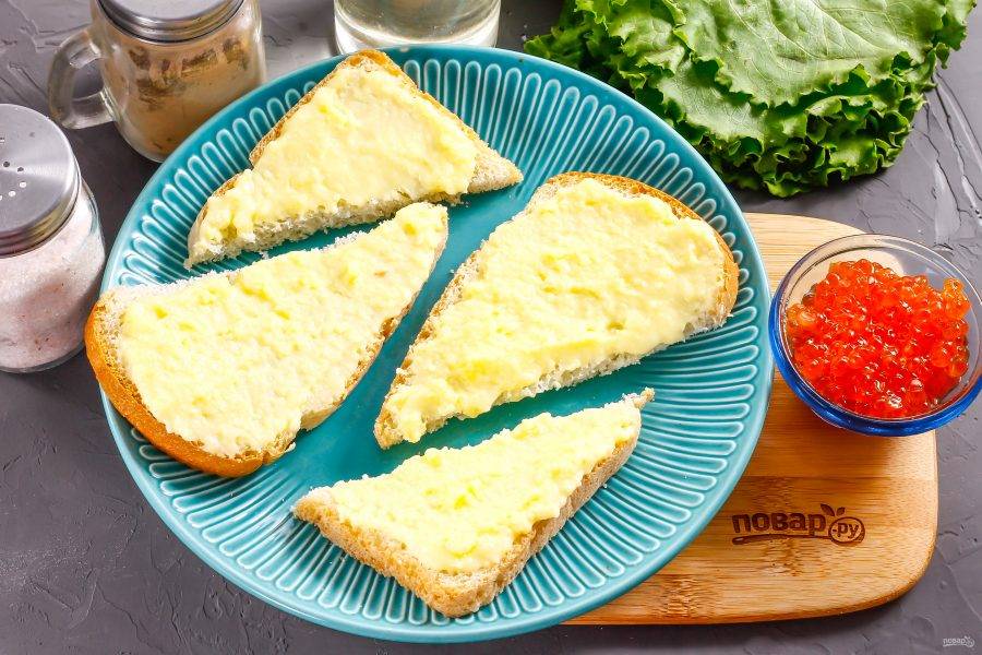 Хлебные ломтики разрежьте по диагонали, чтобы получилось по два кусочка. Обмажьте каждый из них плавленым сыром либо соусом и выложите на тарелки.