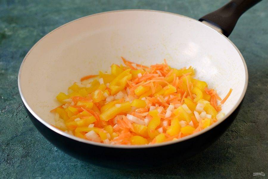 В это время подготовьте все овощи. Морковь помойте, очистите и натрите на крупной терке. Лук нарежьте кубиками. Болгарский перец помойте, удалите семена и нарежьте соломкой. Чеснок мелко порубите. Обжарьте овощи на сковороде до мягкости.