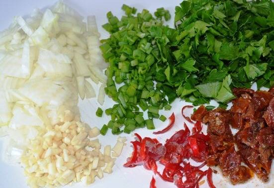 Подготавливаем другие ингредиенты. Репчатый лук нарезаем небольшими кубиками, чеснок, зелень, вяленые томаты и перец чили измельчаем. 