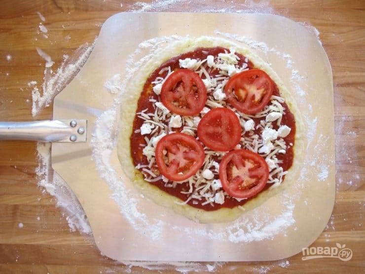 6. Сверху смажьте тесто маслом и соусом. Потом разложите кружки помидоров и натрите сыр.