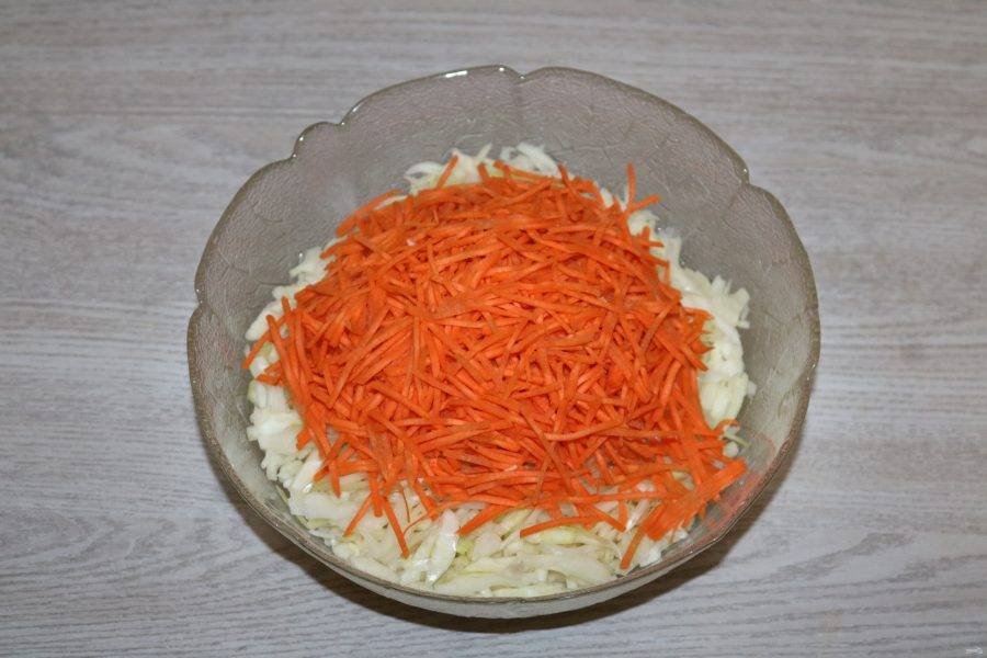 В глубокий салатник переложите капусту и добавьте к ней натёртую морковь.