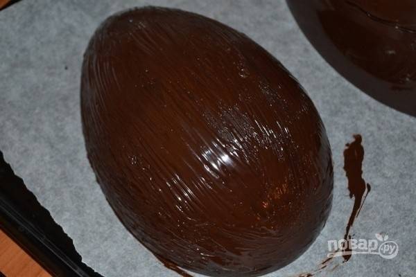 13.	Растопите на водяной бане оставшиеся по рецептуре 200 г черного шоколада, смажьте им половинки шоколадного яйца.