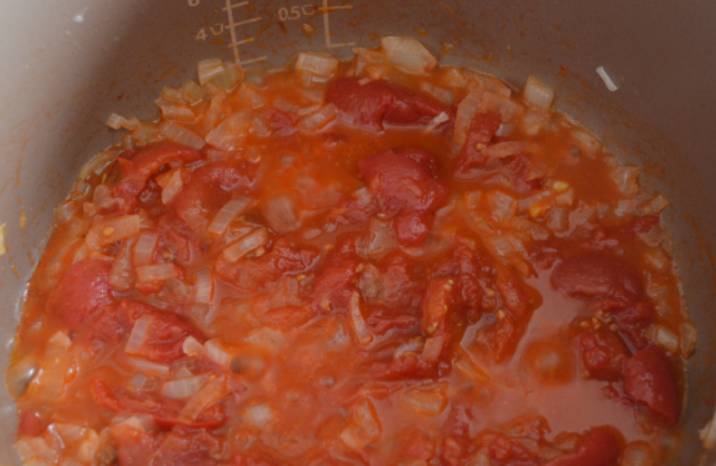 С томатов снимаем кожуру и слегка разминаем их ложкой. Добавляем томаты к луку, готовим вместе 3-4 минуты.