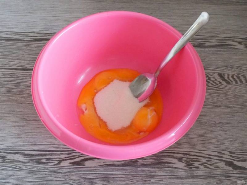 Разделите яйца на желтки и белки. Белки уберите в холодильник. Желтки переложите в чашу. Добавьте сахар и разотрите.