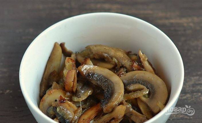 Шампиньоны вымойте и обсушите. Нарежьте грибы на тонкие пластинки. В сотейнике или на сковороде разогрейте растительное масло и обжаривайте в нем грибы пять-десять минут. 
