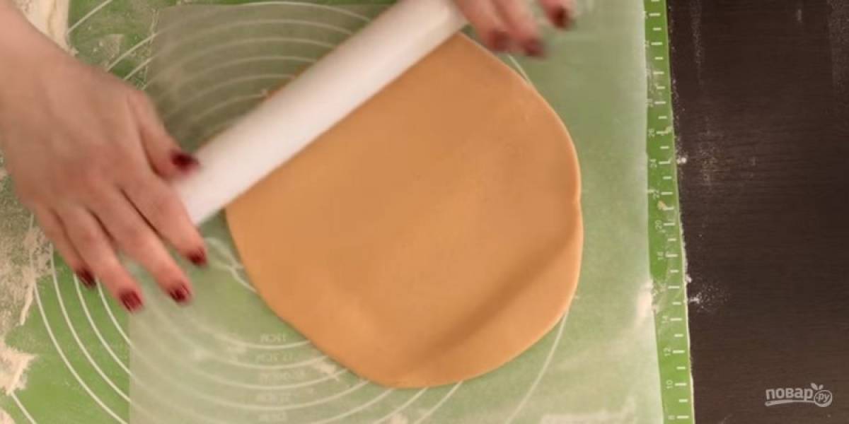 5. Оставьте тесто на столе на 5 минут, после чего разделите его на две равные части. На бумаге для выпечки раскатайте корж диаметром с дно разъемной формы для выпечки. Толщина теста 0,5 см.