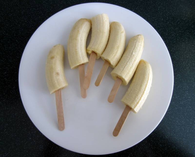 1. Бананы почистите, разрежьте надвое и срезанным концом насадите на деревянные палочки.