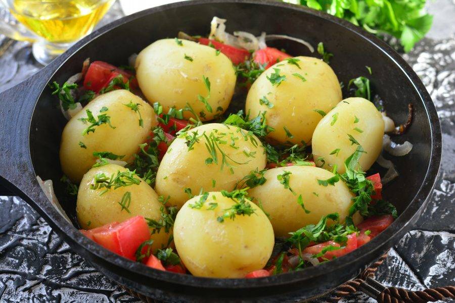Перемешайте картофель с помидорами, держите на огне пару минут. Посыпьте рубленой зеленью и готово.