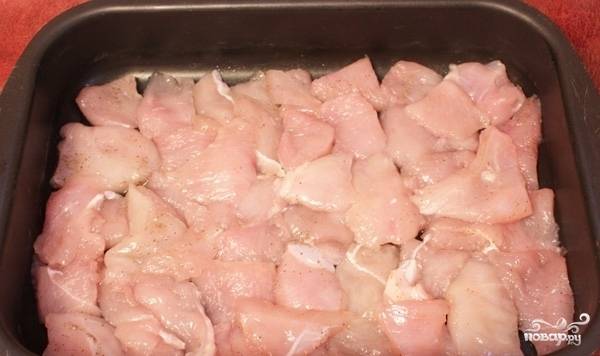 Противень смазываем маслом и выкладываем по всему его периметру нарезанное филе курицы. 