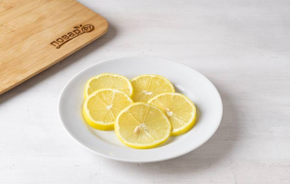 Лимон тщательно помойте и нарежьте на тонкие кружочки. 

