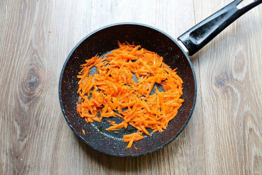 Морковь почистите, сполосните и натрите на крупной терке. В сковороду после грибов влейте оставшееся масло, разогрейте и выложите морковь. Обжаривайте ее в течение 5 минут на среднем огне, перемешивая.