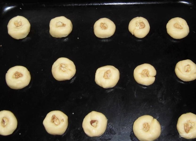 4.	От общей массы мягкого теста отщипываю небольшие кусочки, скатываю каждый в шарик и выкладываю на противень, чищу грецкие орехи, внутрь каждого печенья кладу один орешек. 