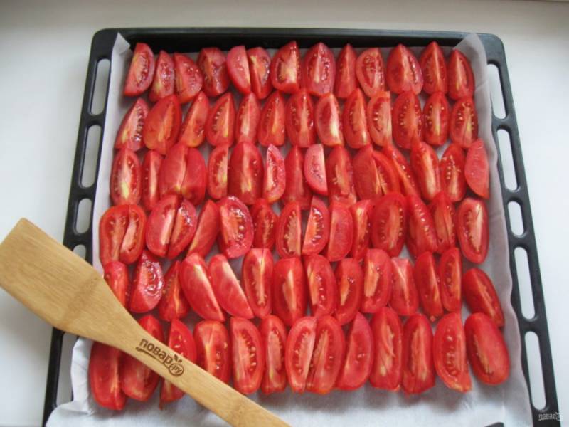 Помидоры помойте, вырежьте место плодоножки и нарежьте дольками. Противень застелите пекарской бумагой и выложите нарезанные помидоры.