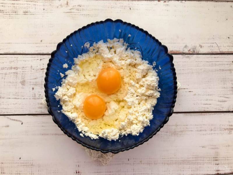 Творог выложите в глубокую тарелку, добавьте к нему яйца и хорошо перемешайте.