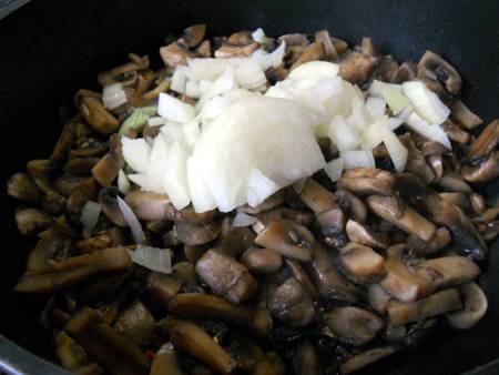 Обжаривать грибы будем на растительном масле.  Когда большая часть жидкости выпариться, добавим мелко нарезанный репчатый лук.