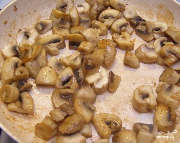 4.	В отдельной сковороде на сливочном масле жарьте грибы. Измельчите чеснок. Положите сверху грибов. Продолжайте жарить. Грибы помешивайте. Готовьте 10 минут. Выжмите из лимона сок. Налейте в сковороду с мясом. Перемешайте.