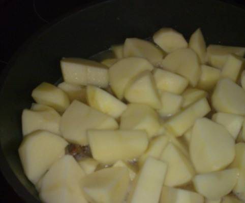 Сверху выкладываем картофель, порезанный крупно. Заливаем все кипятком, чтобы покрылась картошка. Тушим под крышкой 8-10 минут до полуготовности.