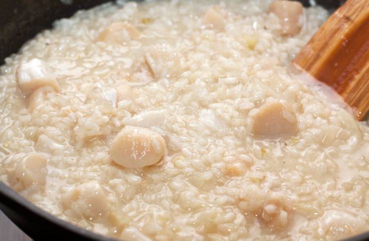 В почти готовый рис добавьте гребешки. Готовьте до состояния "аль денте", чтобы рис оставался упругим и в то же время плотным внутри. 