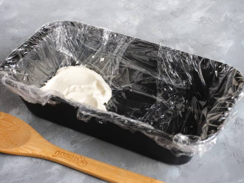 Прямоугольную форму для кексов оберните пищевой пленкой и начнем собирать торт. Первым слоем выложите крем толщиной примерно 1-1,5 см.