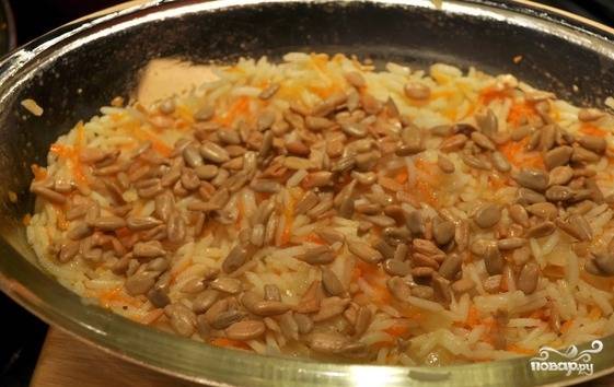 Смешайте рис с морковью и луком. Уложите эти ингредиенты следующим слоем. Сверху посыпьте семечками. Потом уложите индейку.