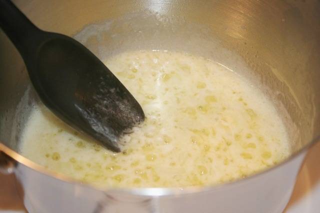 Пока голени запекаются, мы для соуса растапливаем в сотейнике три ложки сливочного масла. Выкладываем в масло нарезанный лук-шалот и измельченный чеснок, жарим все до мягкости, после чего добавляем муку и еще пару минут все обжариваем, постоянно помешивая. Затем вливаем в сотейник бульон и молоко, продолжаем нагревать соус, помешивая его, пока он не загустеет. После этого снимаем соус с огня, добавляем в него щепотку мускатного ореха и тертый сыр, перемешиваем все, пока сыр не растает. 