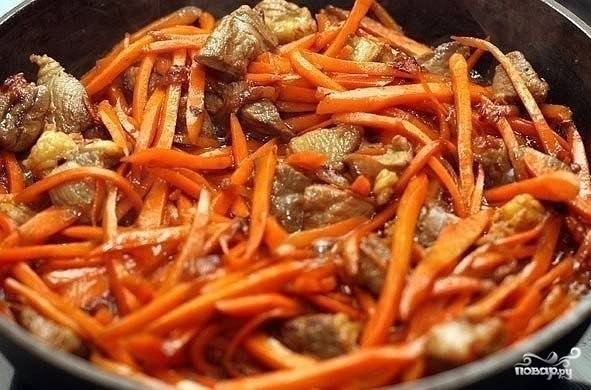 Добавляем к мясу подготовленную морковку, перемешиваем и обжариваем минут 7-10, не забывая перемешивать. Морковь должна стать мягкой.