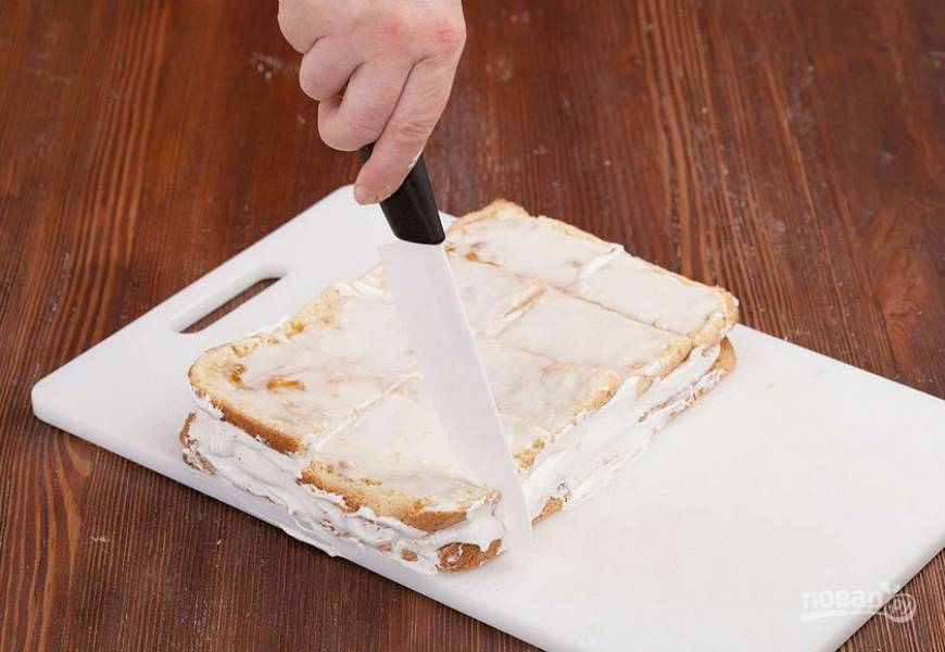 Нарезаем бисквит порционными кусочками. Боковую сторону каждого пирожного присыпаем крошками.