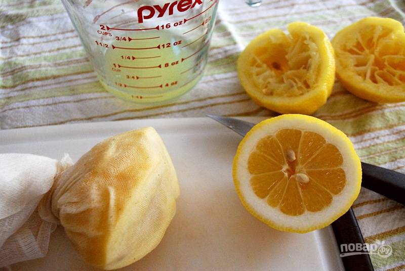 Лимоны очень хорошо вымойте и нарежьте на половинки. При помощи вилки помните мякоть лимонов, а затем поочередно оберните части фруктов марлей и отожмите из них сок.