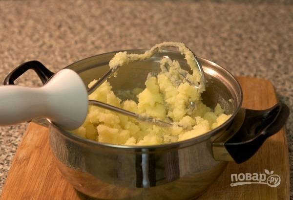 3. В кастрюлю добавьте сливочное масло, начните мять картофель. 