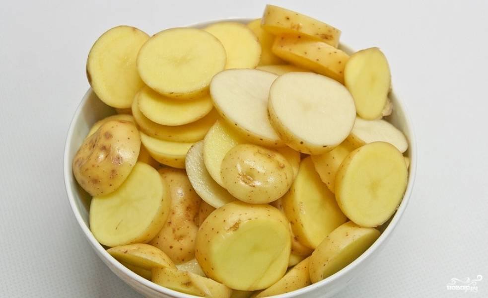 1. Перед тем как приготовить слоеную картошку со свининой, помойте молодой картофель. Порежьте его кружочками приблизительной толщиной в 1см. 