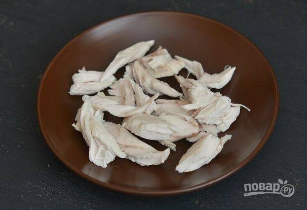 Куриное филе вымойте, обсушите бумажными полотенцами и зачистите от пленок. Отварите в подсоленной воде курицу до готовности, слейте воду, остудите. Разделите мясо на волокна.