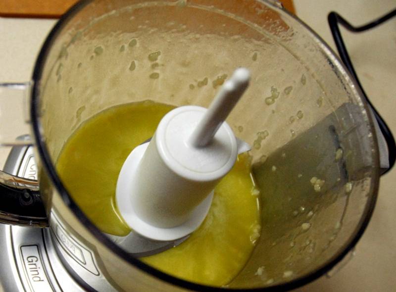 Ставим вариться пасту согласно инструкции на упаковке, а сами тем временем займемся соусом. Для него нам нужно налить в чашу блендера оливковое масло, добавить лимонный сок и чеснок. Включаем блендер и измельчаем все до однородного состояния.