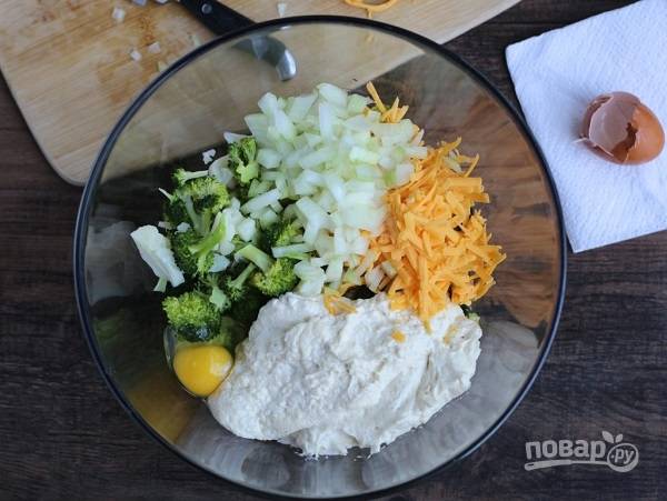 4. В глубокой мисочке соедините брокколи, измельченный кубиками лук, тертый сыр (часть отложите), яйцо и сырный соус. Посолите и поперчите по вкусу, аккуратно все перемешайте. 
