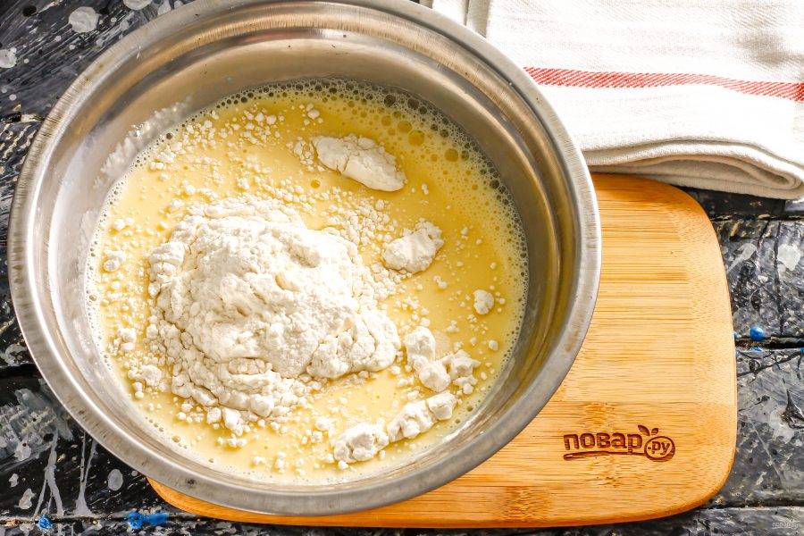 Взбейте куриные яйца в глубокой емкости с молоком, добавьте две щепотки соли. Всыпьте пшеничную муку и замесите блинное тесто. Влейте в него растительное масло, оставьте тесто на 15 минут для активации клейковины.