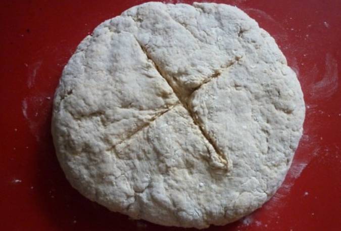 Замесите тесто. Присыпьте противень мукой и сформируйте буханку хлеба. По центру сделайте надрез в форме креста. Выпекайте хлеб в духовке 35 минут, температура 200 градусов.