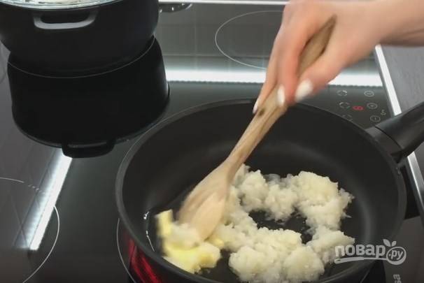 5. На сковороду выложите сливочное масло и добавьте подсолнечного. Луковицу нарежьте очень мелко или подробите в блендере. Отправьте на сковороду, пока она холодная. Лук должен впитать в себя масло и начать тушиться. Добавьте щепотку соли.