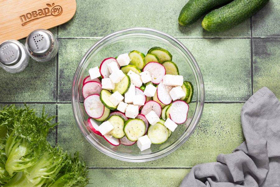 Нарежьте сыр фета кубиками, добавьте в миску. Полейте салат заправкой.