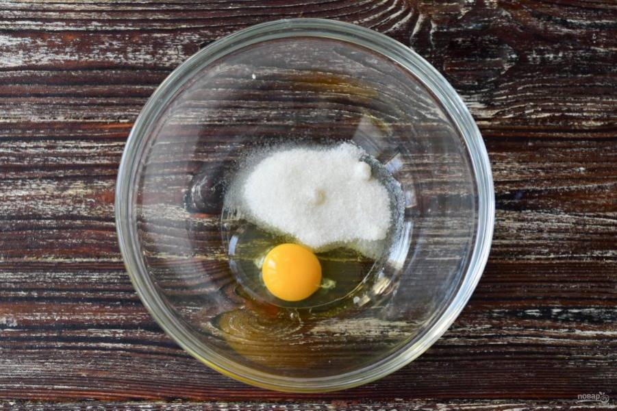 В миску вбейте яйца, и всыпьте сахар.