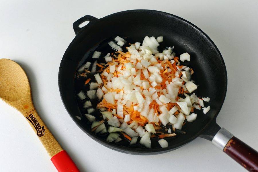 Пока овощи варятся приготовьте зажарку. Разогрейте сковороду с маслом и положите нарезанный кубиками лук и тертую морковь.