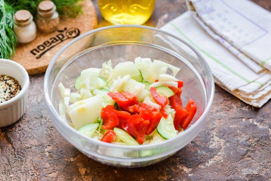 Сладкий перец нарежьте полосками и добавьте следом за огурцами в салатник. Также очистите и нарежьте кубиками лук, переложите в салат.
