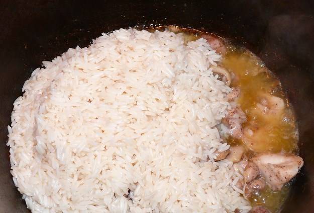Как мясо прожарится почти, выкладываем промытый рис.