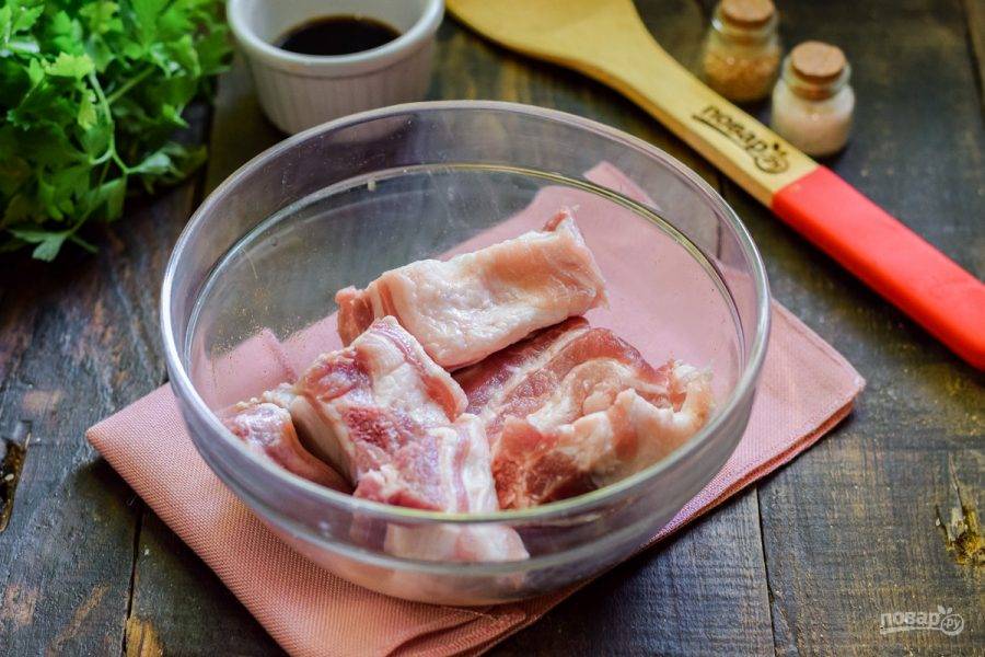Свиные ребра ополосните и просушите, нарежьте порционно и переложите в миску.
