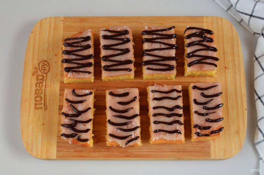Порежьте бисквит на 8 частей. Растопите шоколад, переложите в корнетик, сделайте полоски на пирожных. Я сделала несколько вариантов: ровные полосочки, закругленные, прерывистые, волны. Выбирайте какой вам нравится вариант или придумайте свой.