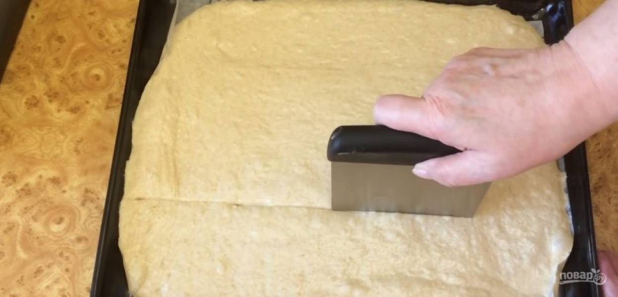5.  Переверните тесто и аккуратно выложите на противень, покрытый пергаментом. Растяните тесто по всему противню смазанными маслом руками. Нарежьте тесто на квадратики и сделайте несколько небольших надрезов на каждом.